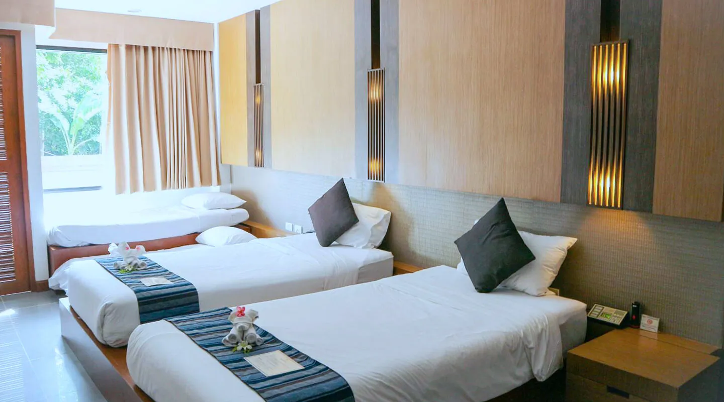 Bright grand deluxe family room with three neatly made single beds, soft lighting, and modern wooden décor at Peach Blossom Resort