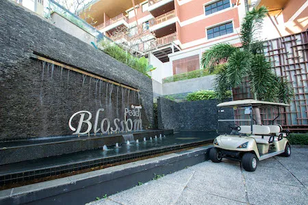 Entrance of Peach Blossom Resort featuring a waterfall wall with the resort name and a golf buggy parked nearby
