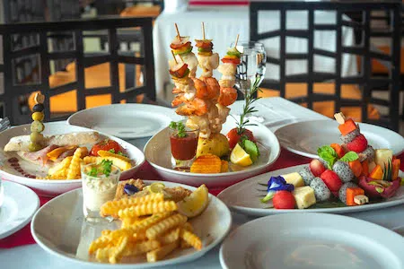 Assorted dishes including seafood skewers, fruit platter, fries, and appetisers served at Peach Blossom Resort restaurant
