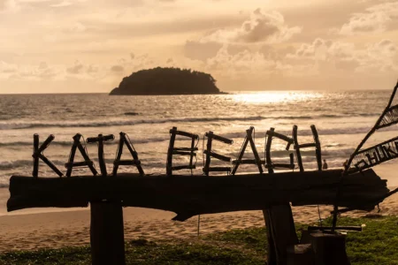 Scenic sunset at Kata Beach with wooden sign and island view in Phuket